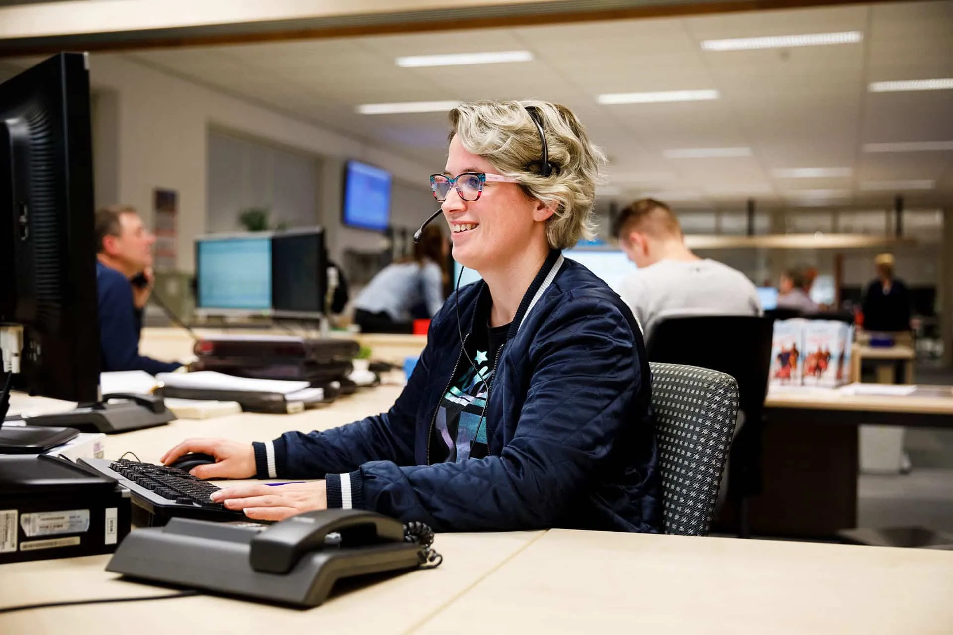 kantoormedewerkster met headset op aan het werk achter haar computer