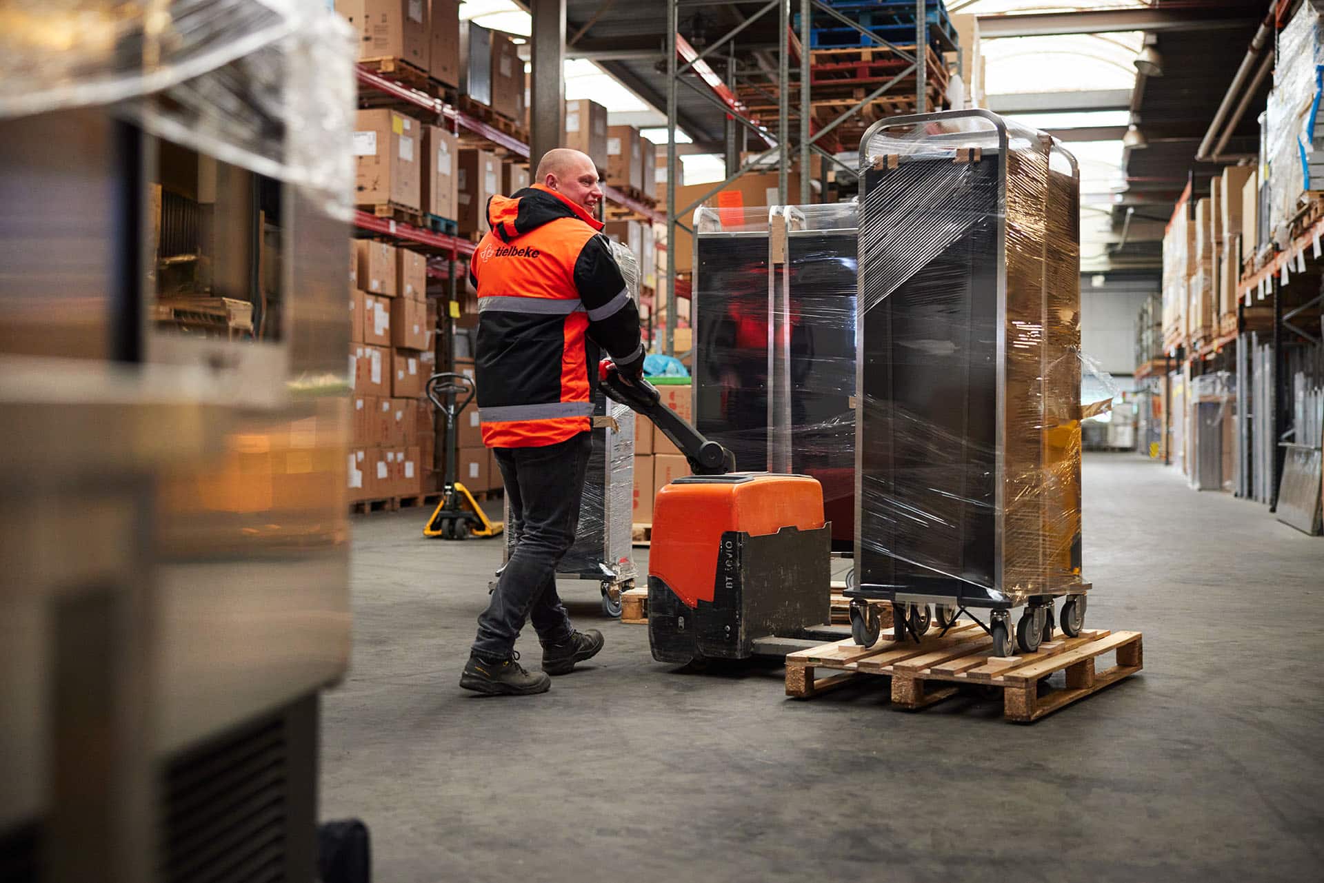 Chauffeur loopt in warehouse met pallet